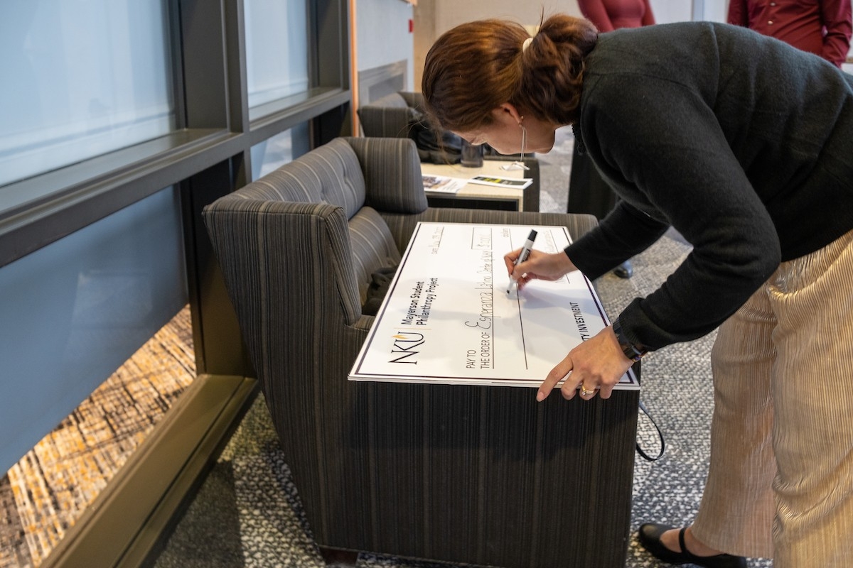 An attendee writes on a presentation check.