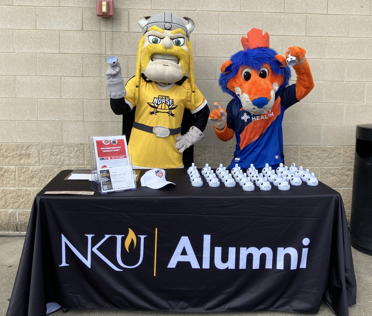 Victor Viking mascot posing FC Cincinnati mascot Gary at an NKU alumni table.