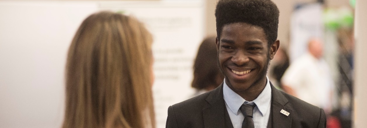 Student smiling while talking to an employer at a career fair