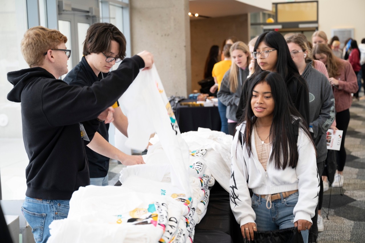 Volunteers handing out shirts to students standing in a line outside the SU ballroom.