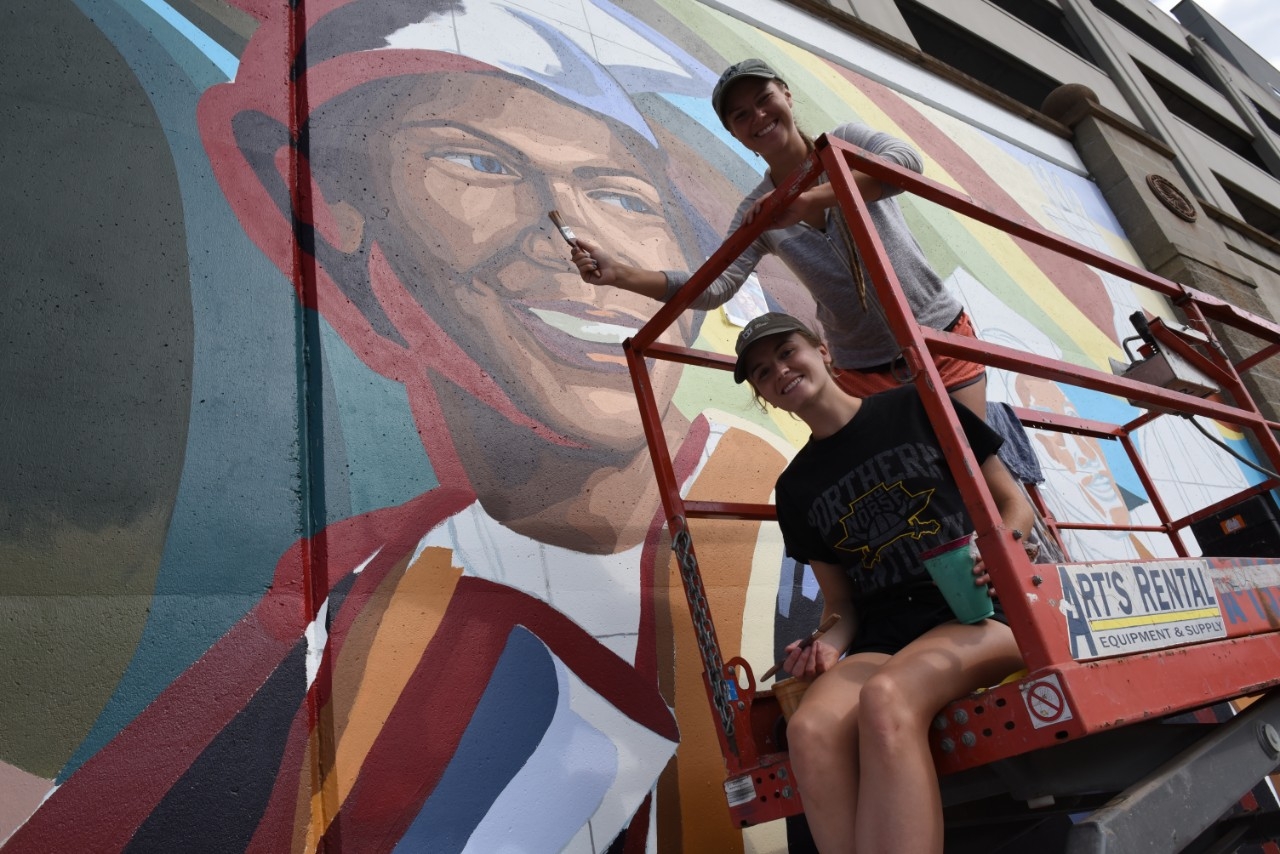 Painters posing next to their wall mural