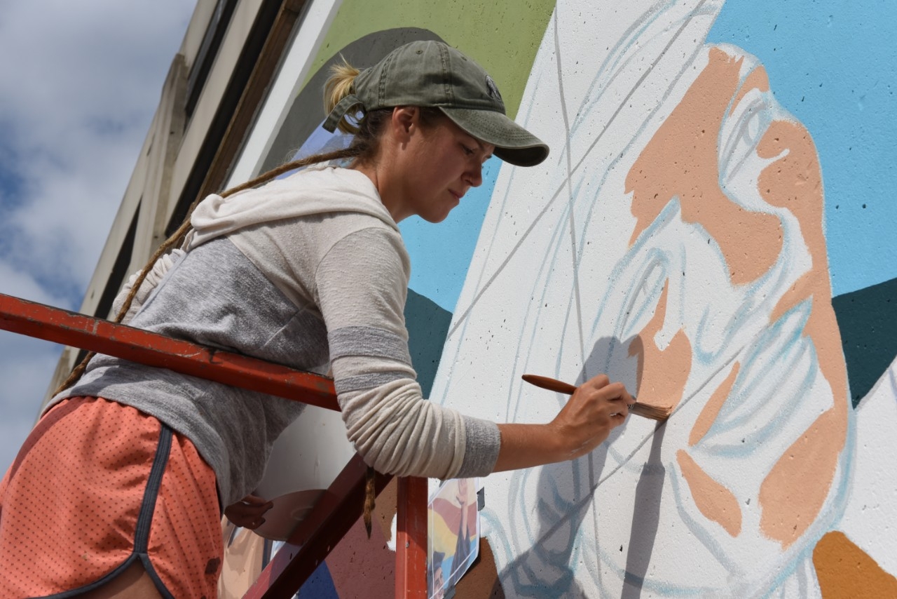 Volunteer painting mural outside.