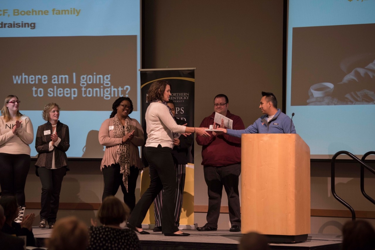 Presenter at Mayerson event handing certificate to winner.