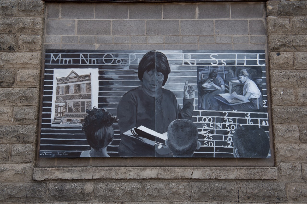 Mural depicting woman reading to students.
