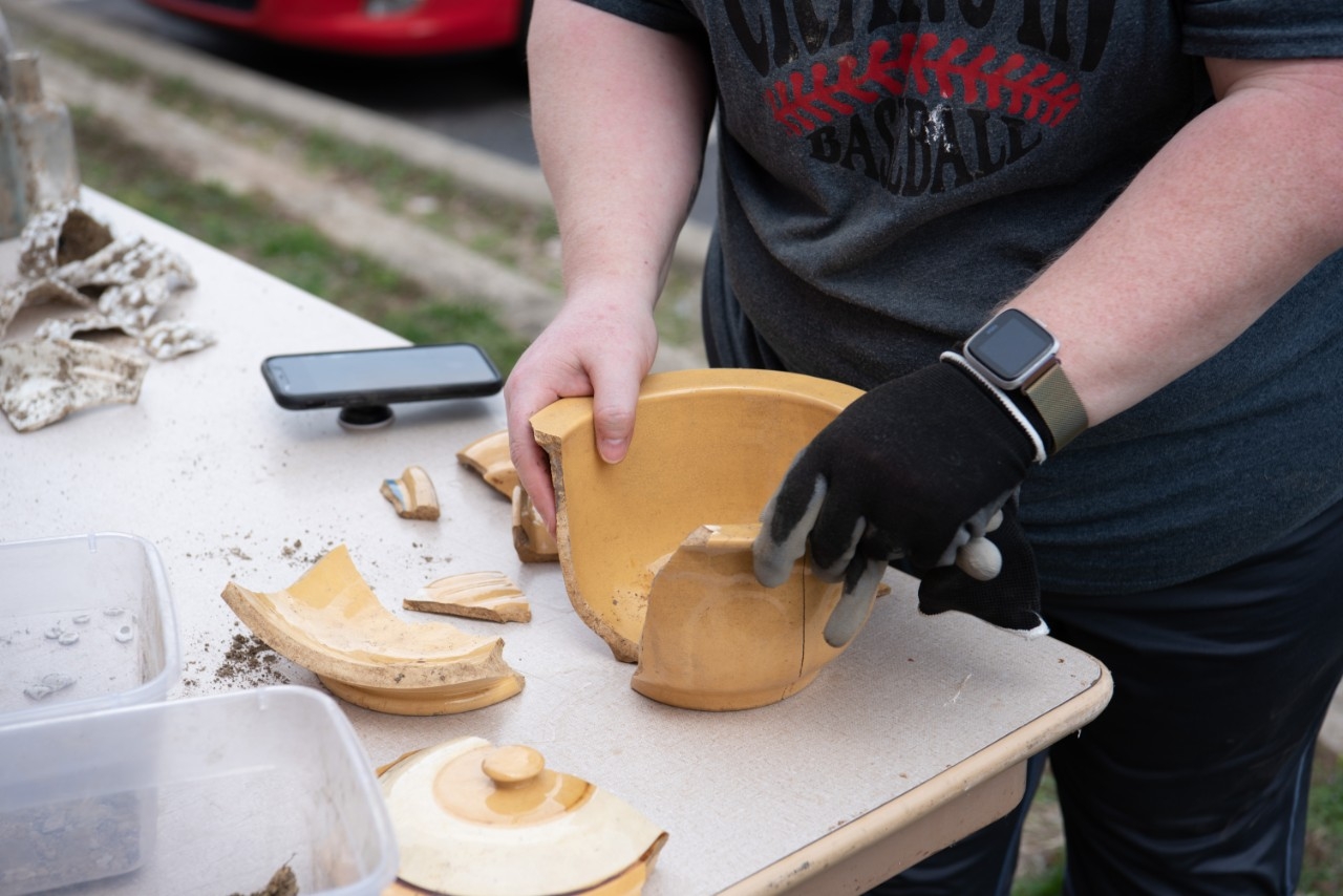 Person assembling a broken pot back together.