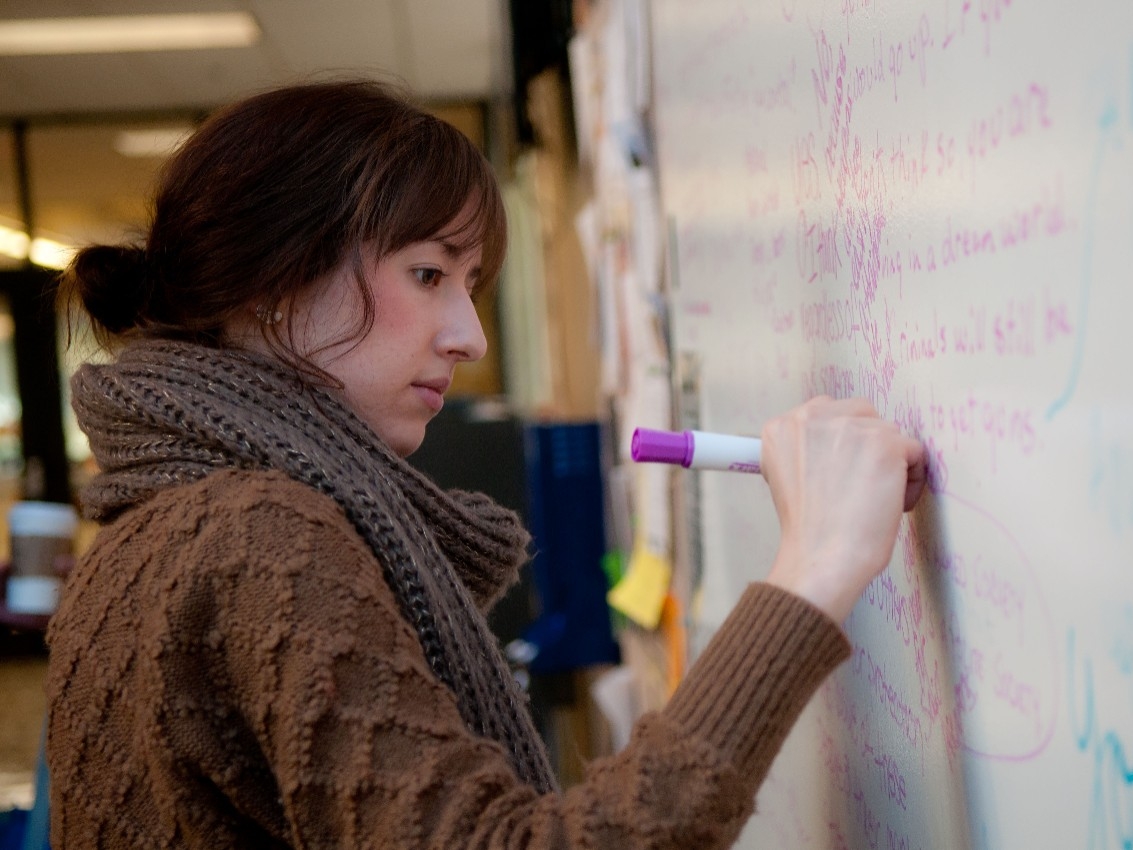 Student writing on Democracy Square marker board.