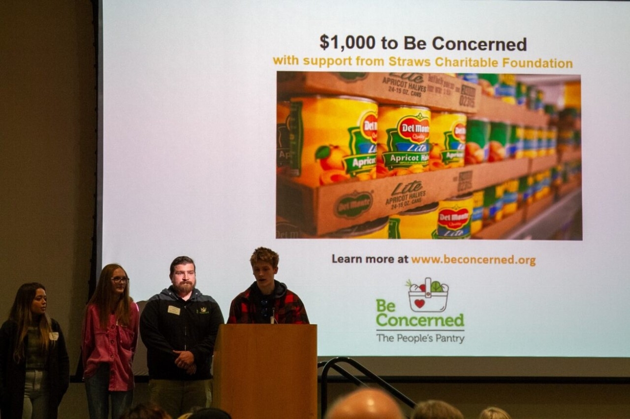 A student presents an award to the nonprofit Be Concerned.