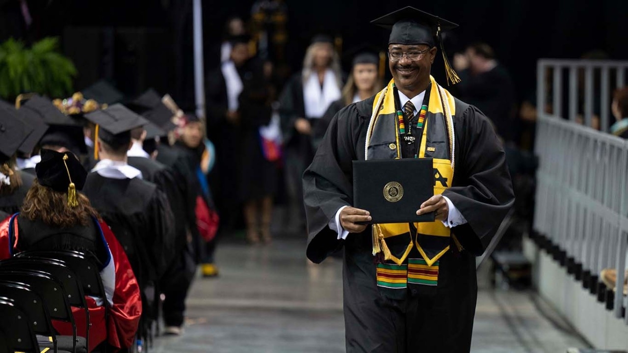 Graduating student walking at NKU commencement ceremony