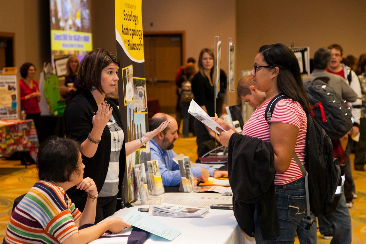 Student talking to person at booth at Major-Minor fair.