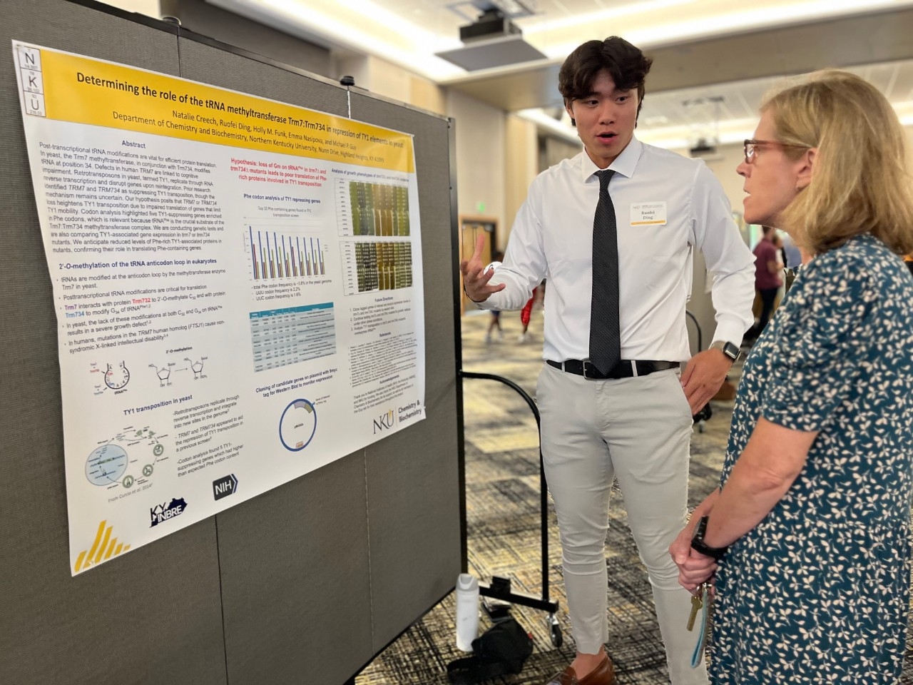 A student presenting his research poster to a faculty member