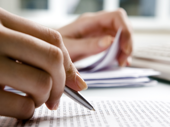 hand holding pen, writing on a document.