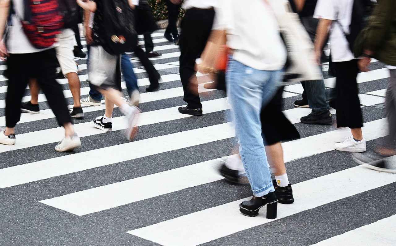 Group of people from the waist down crossing the street at a crosswalk.
