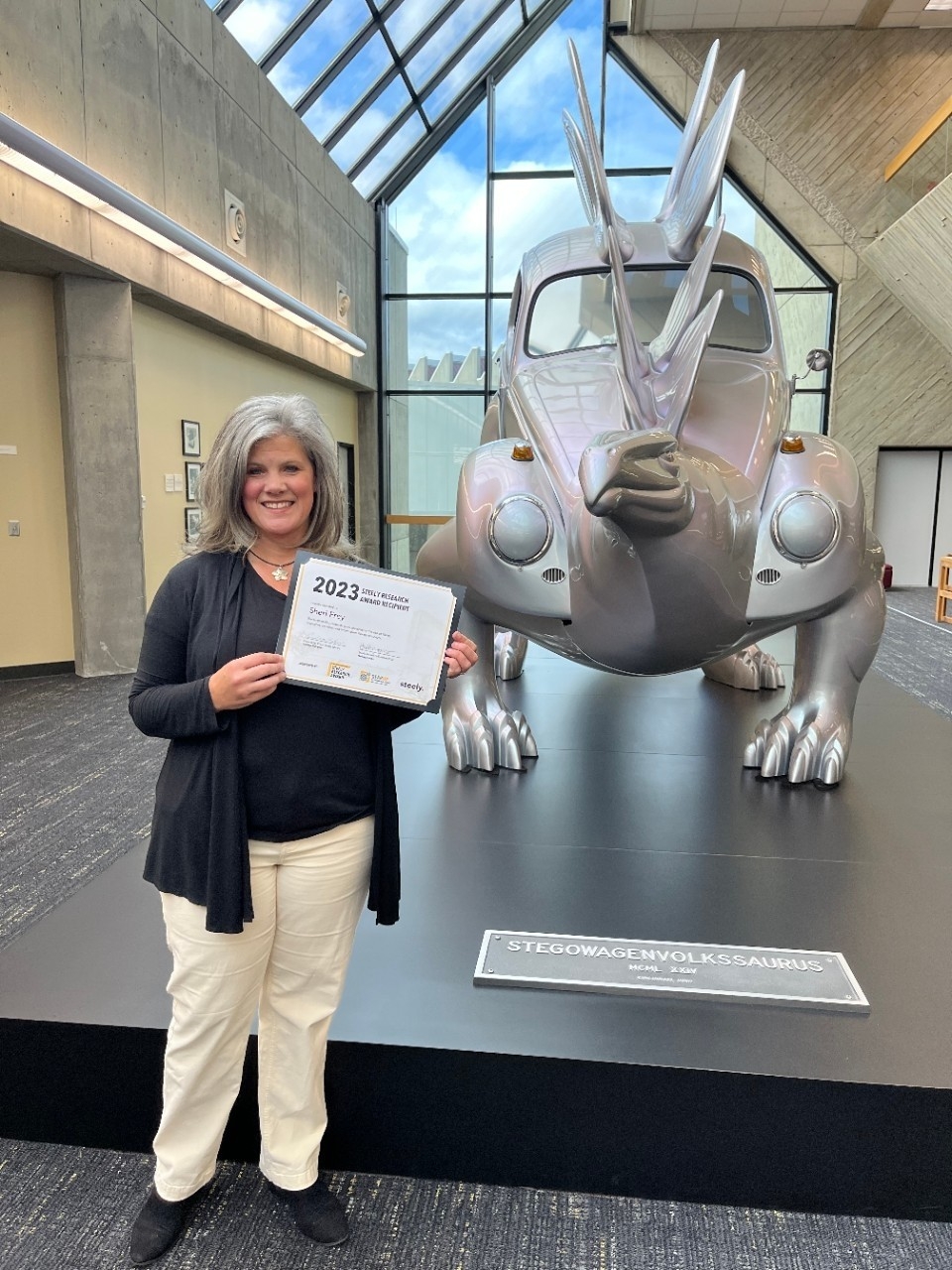 2023 Steely Research Award Recipient Sheri Frey standing next to the Steggo statue in the library.