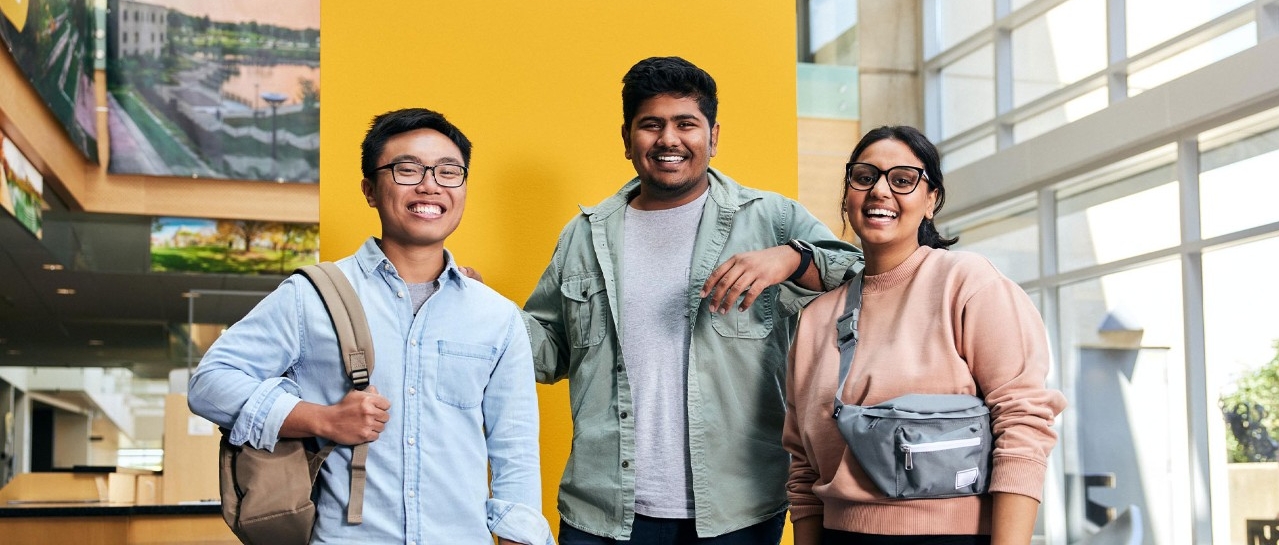 Students in the SU posing for the photographer in front of a yellow panel