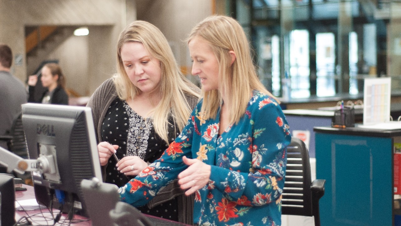 Librarian and student in the library at one of the computer terminals.