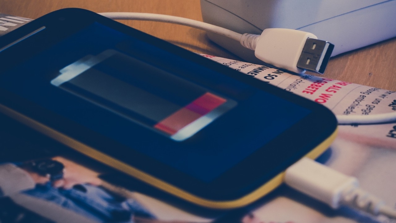 Phone with USB charging cord on desk.