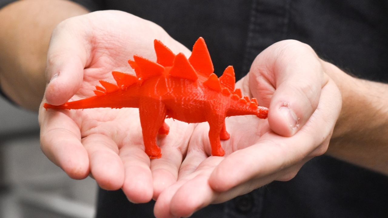 Man holding small dinosaur 3D print in his hands.