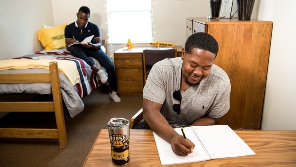 Student in dorm sitting at desk doing homework 