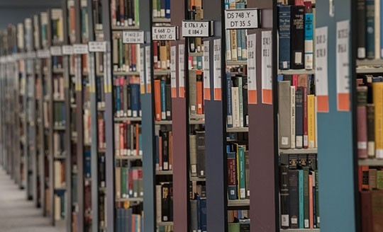 An angled view of book shelves full of resources at the Steely Library