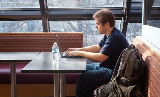 Student sitting at a table working on a laptop