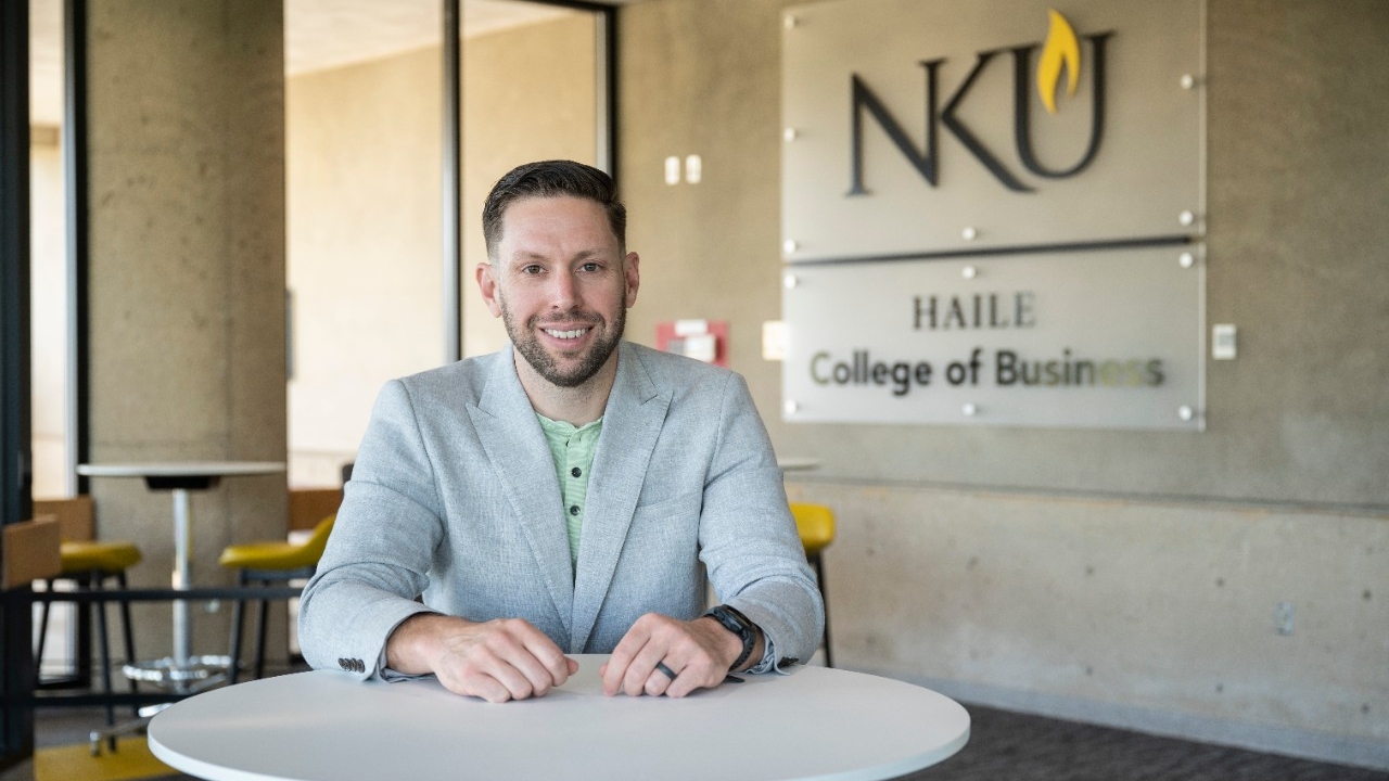  Zac Strobl sits at desk in the College of Business lobby
