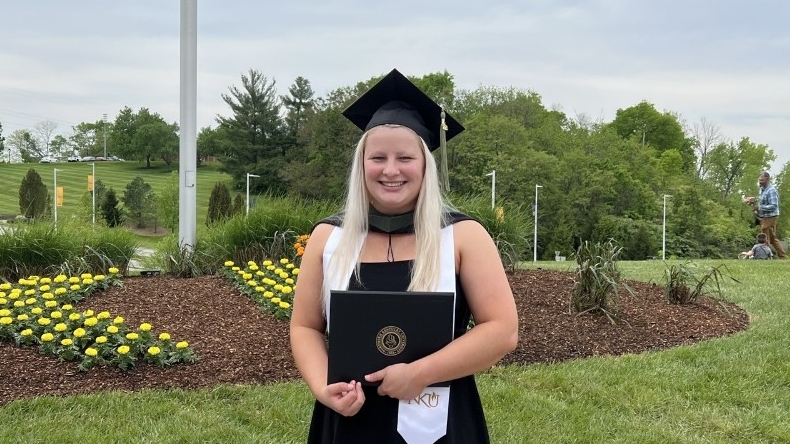  Haley Berry holds diploma on campus on graduation day.