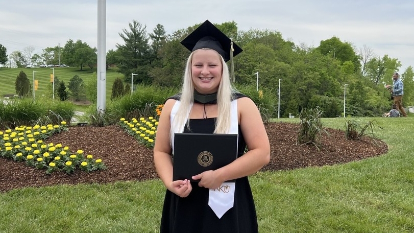  Haley Berry holds diploma on campus on graduation day.