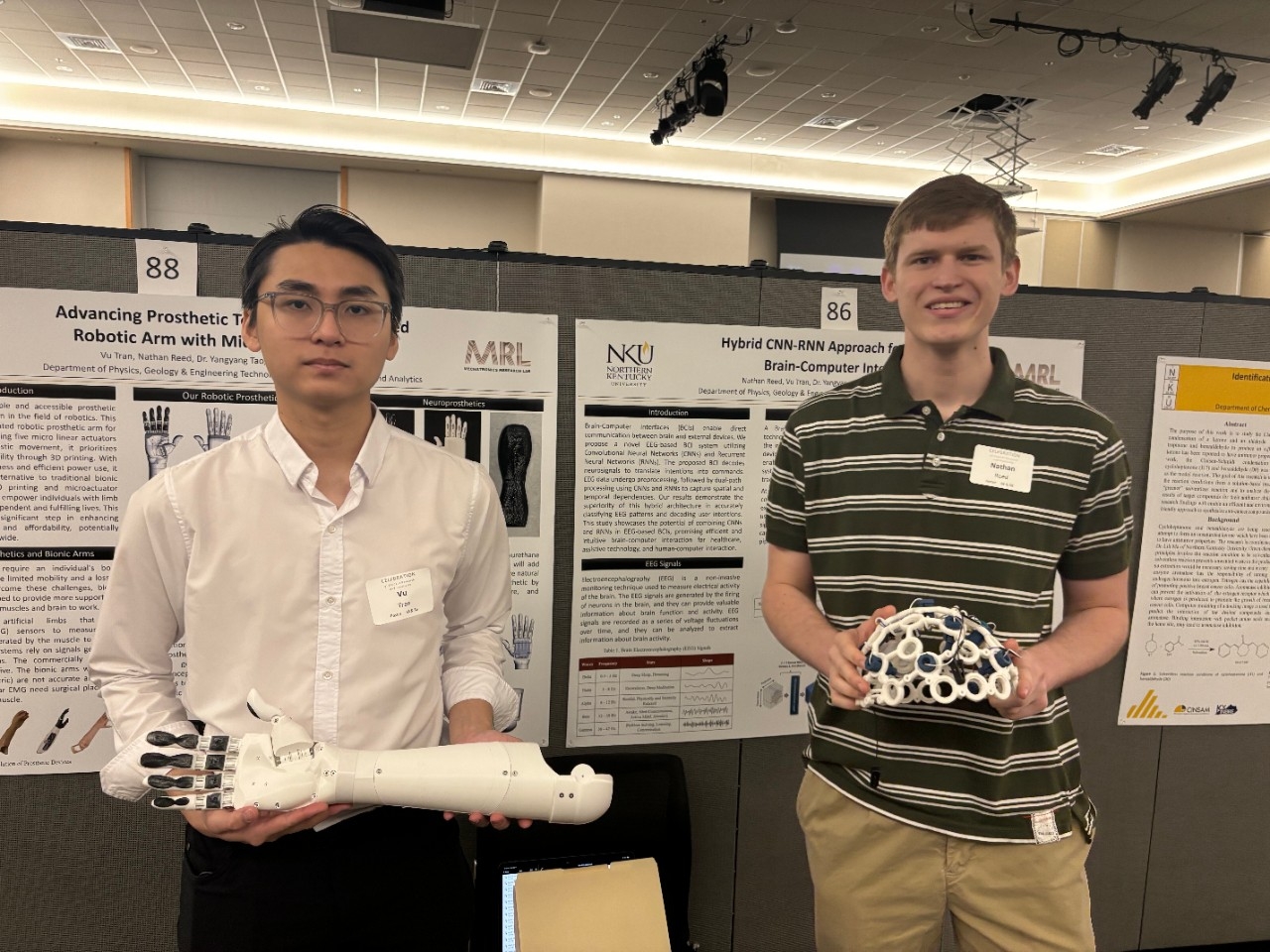 Students hold a prosthetic arm in front of their project poster