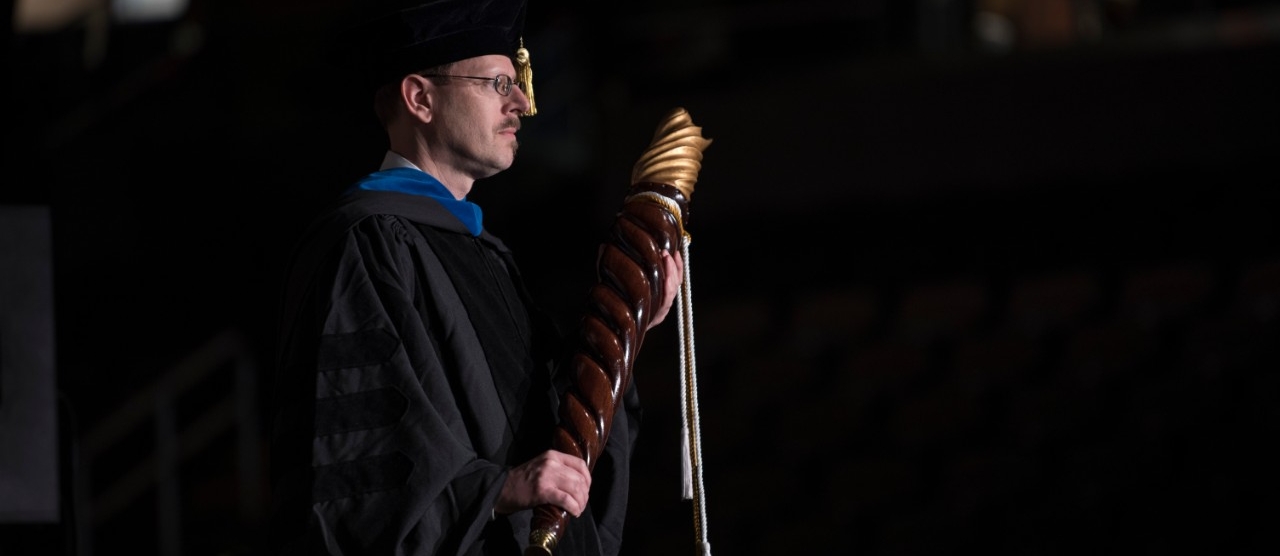 Man holding the university mace during commencement