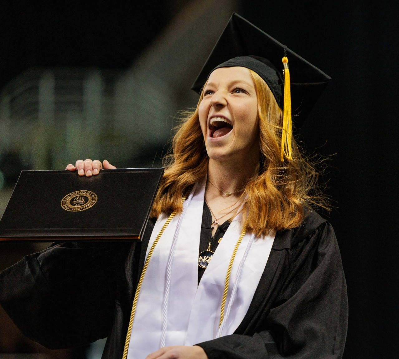 Female student excitedly holding up diploma 