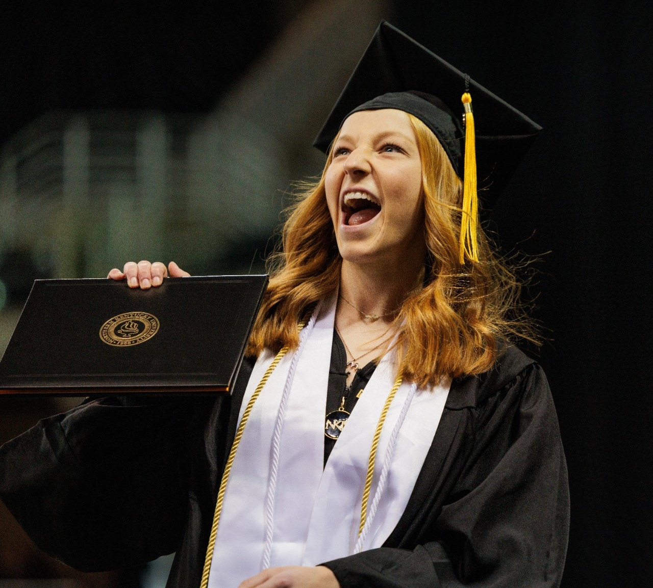 Female student excitedly holding up diploma 