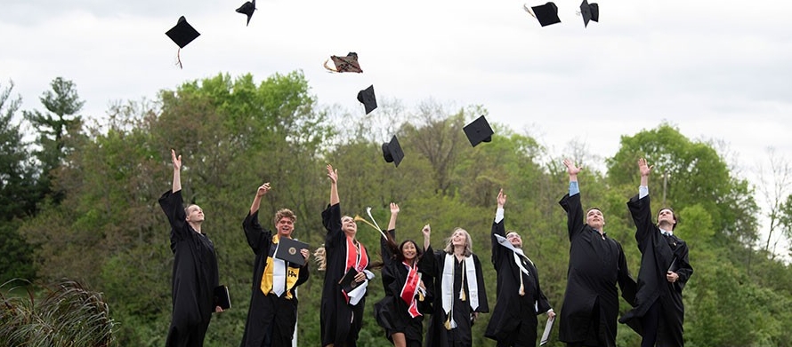NKU graduates celebrating by tossing their caps in the air