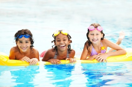 Young kids swimming in pool smiling at camera