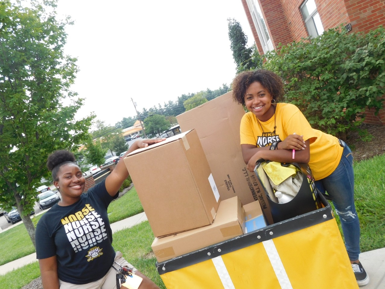 Photo of two smiling students moving into housing