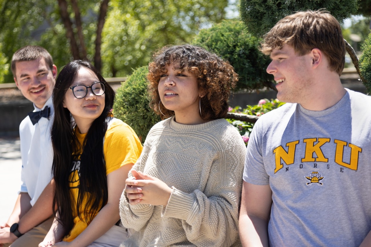 Four students talking to each other outdoors.