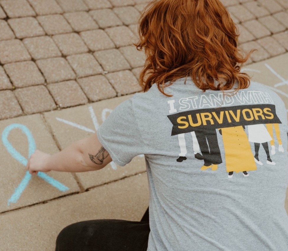 Student writing with chalk on the plaza. 