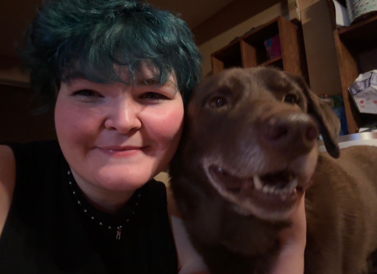 Photo of student smiling with a brown dog.