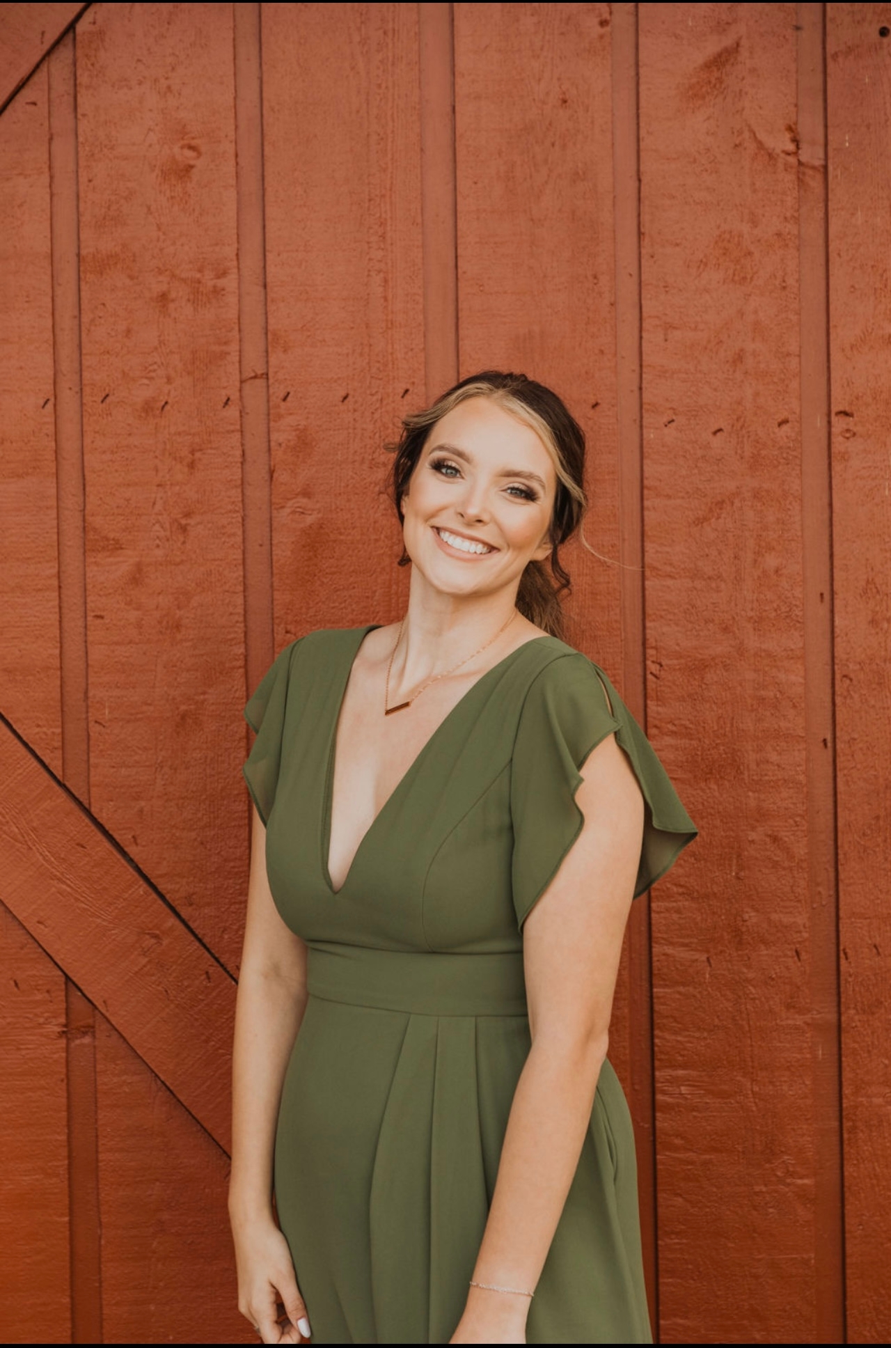 Photo of Karlyn in a green dress standing in front of a wood background.