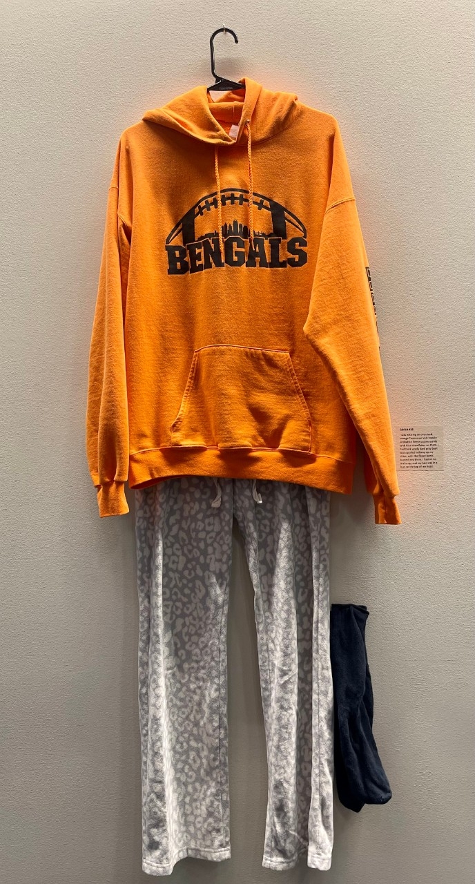 orange hooded sweatshirt, gray sweatpants, long black socks