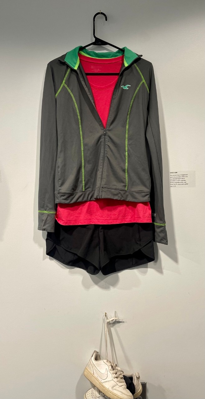 Pink t-shirt with grey athletic jacket over top, black running shorts, white sneakers