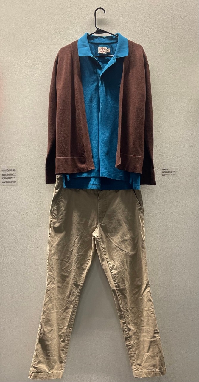 A blue polo shirt under a brown button up cardigan sweater with khaki pants.