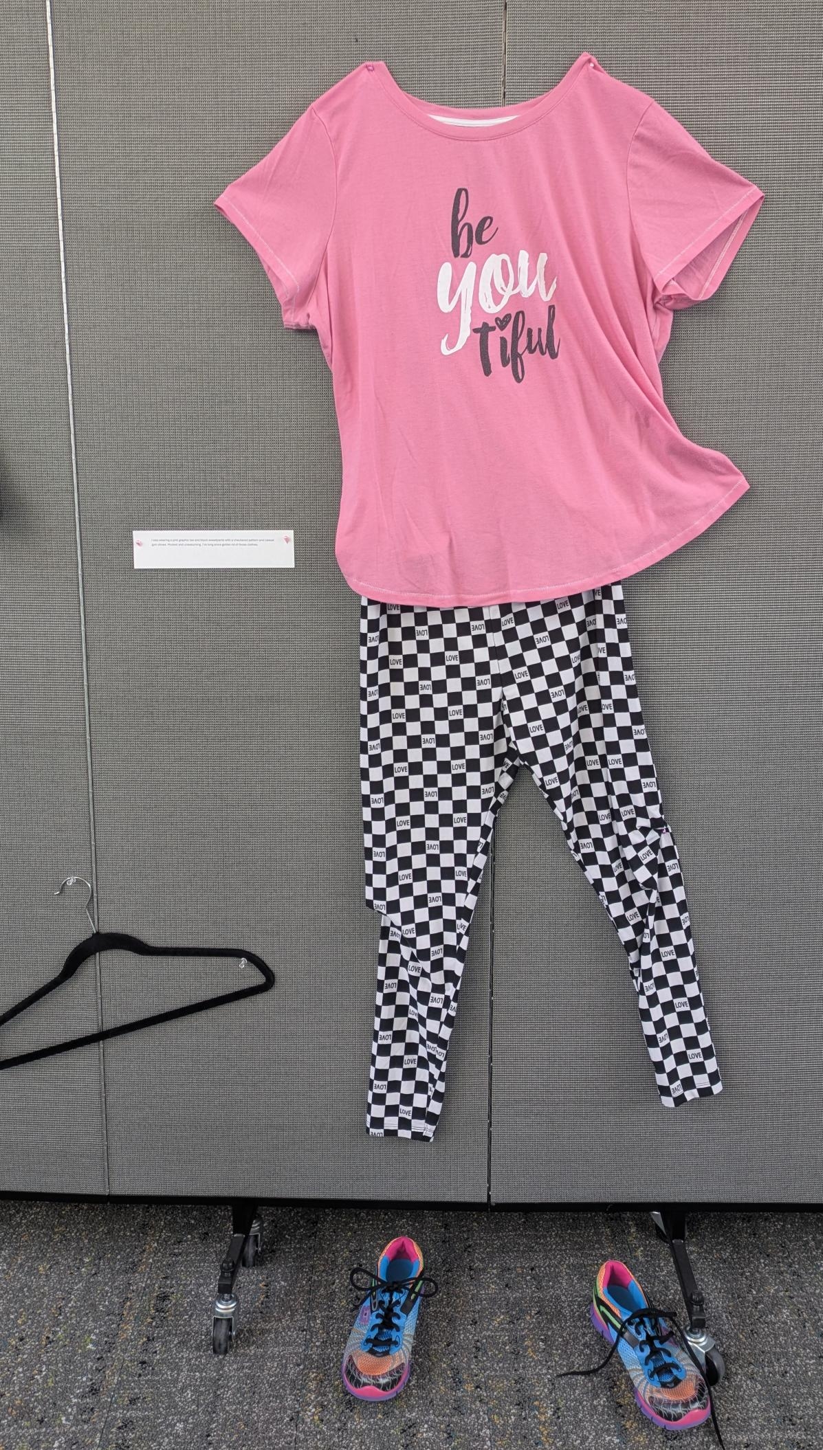 Pink graphic tshirt with black checkered pants and sneakers.