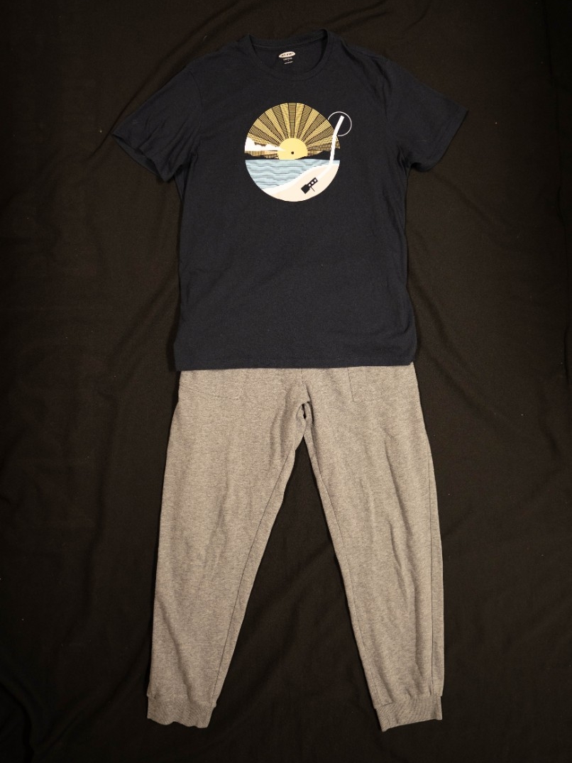 Exhibit displays gray sweatpants and a black t-shirt with a vinyl record on it. 