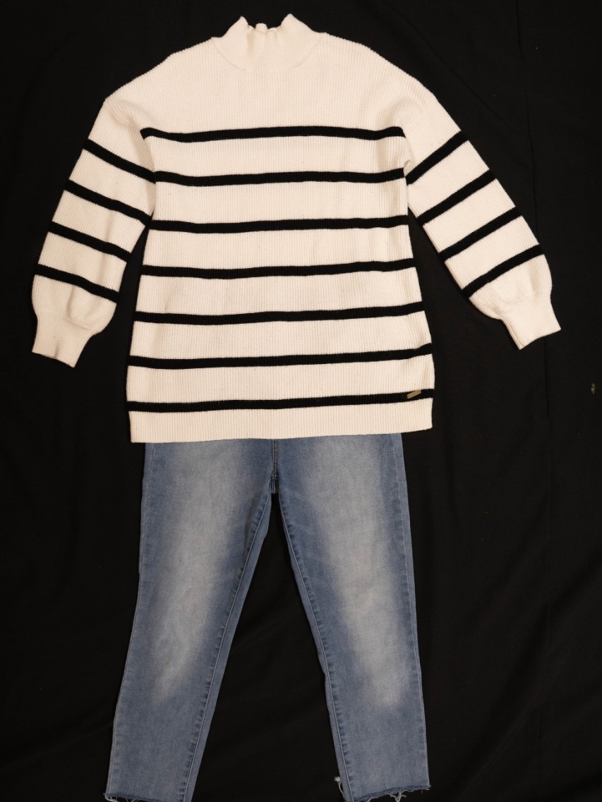 Exhibit displays a white sweater with black stripes and standard jeans.