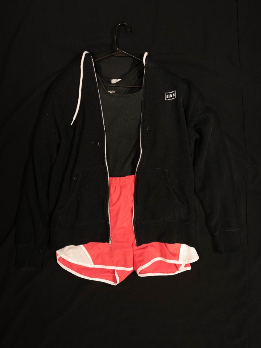 Exhibit displays a black cropped tank top, pink athletic shorts, and a black zip up.