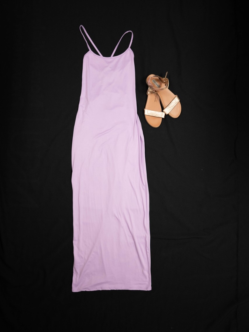 Exhibit displays a medium length lavender dress with gold sandals. 