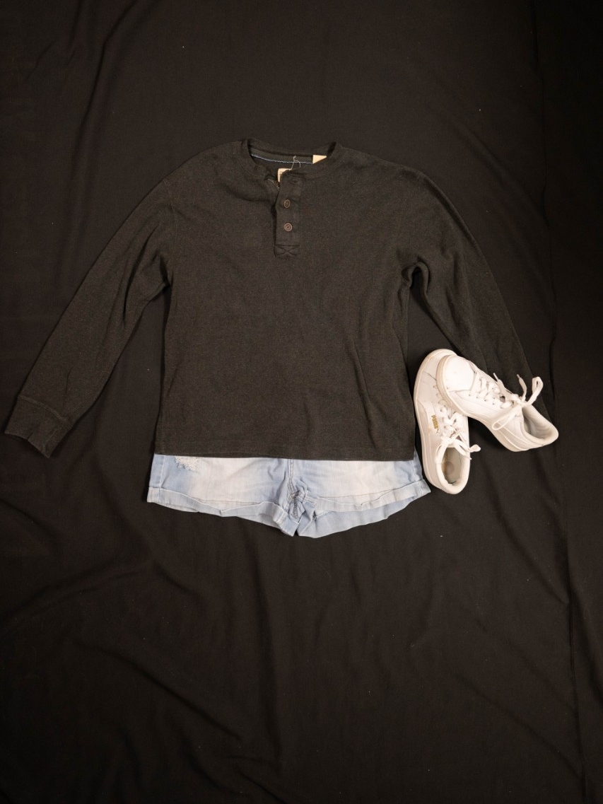 Exhibit displays a gray crewneck and light wash jean shorts and white sneakers. 