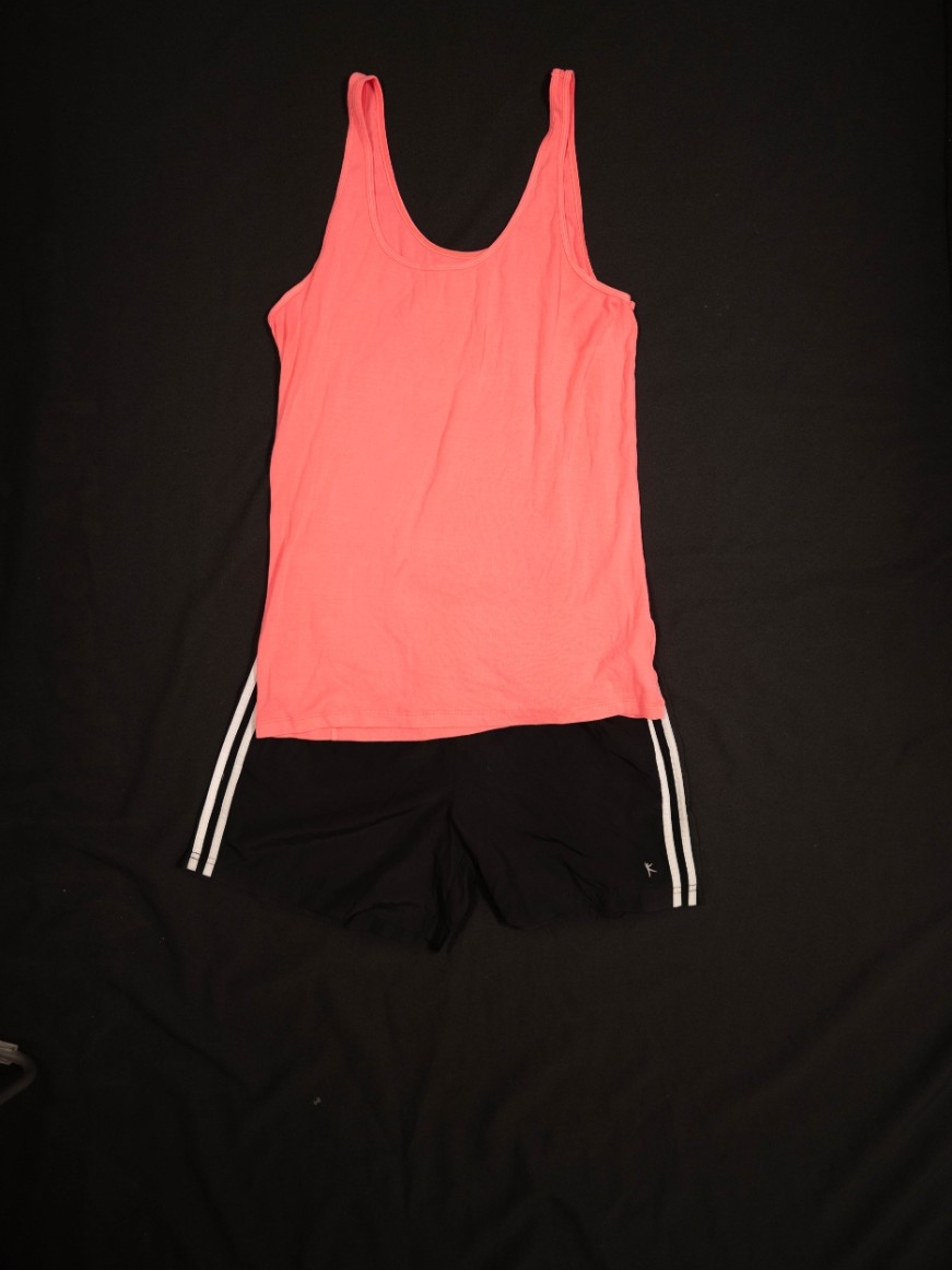 Exhibit displays a pink athletic tank top with black athletic shorts. 