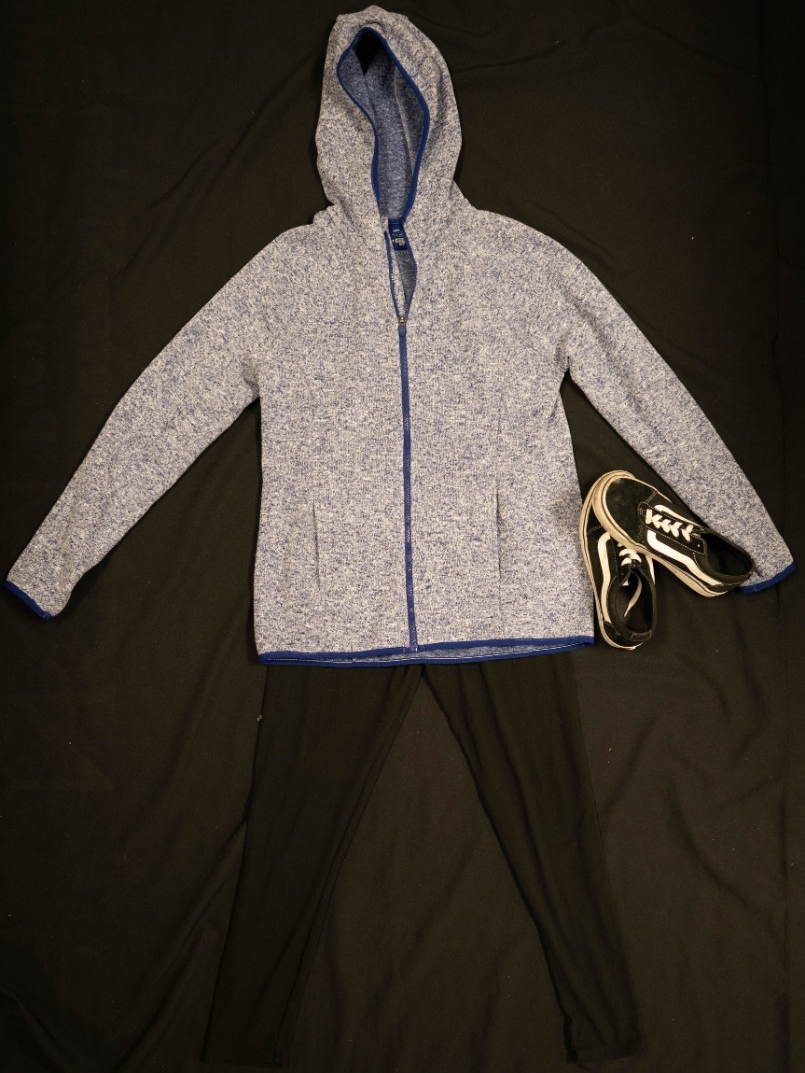 Exhibit displays a blue zip up hoodie, black leggings, and black sneakers. 