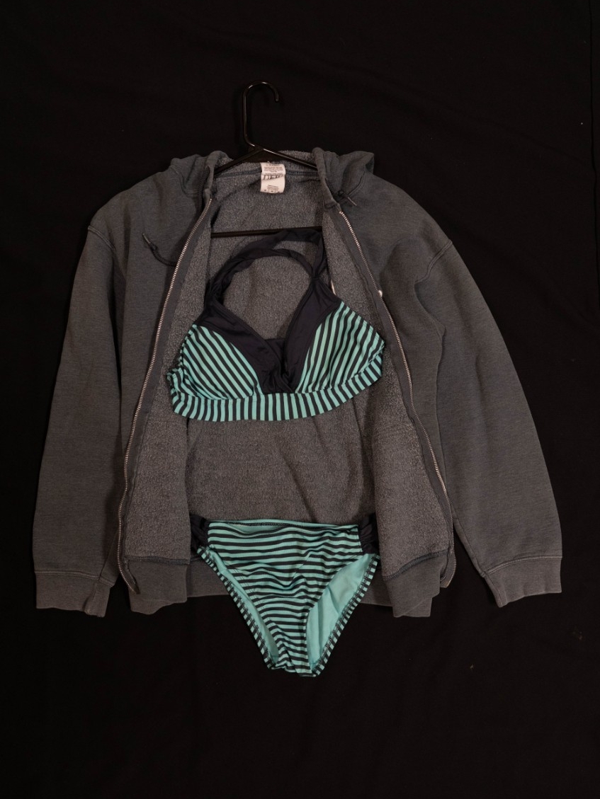 Exhibit displays a teal and black striped bikini with a gray zip up.